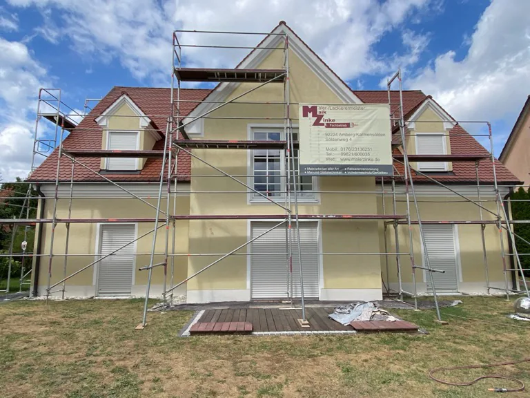 Einfamilienhaus komplett eingerüstet mit dem Banner von Malerfachbetrieb Maik Zinke an der Fassade